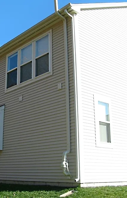 An installed radon mitigation fan and pipe run on the exterior of a home